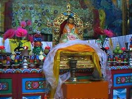 Detail of altar showing a Buddha statue and white and yellow kathak.