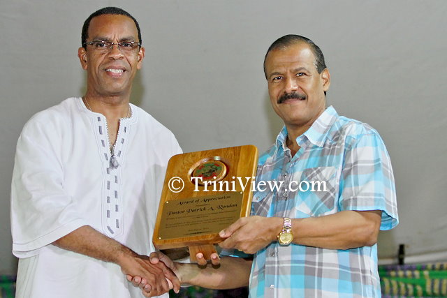 (L) Minister, the Honourable Rodger Samuel, presents a token of appreciation to Pastor Rondan