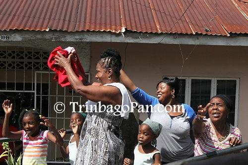 Members of the Laventille community cheer and wave as the motorcade passes