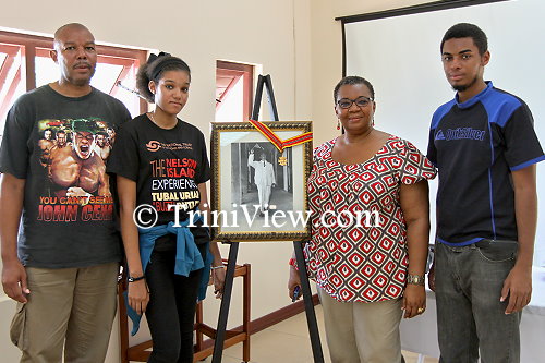 Tubal Uriah ‘Buzz’ Butler’s grandchildren and great-grandchildren pose with an image of him with the Trinity Cross, the nation's highest award at the time which he received in 1970